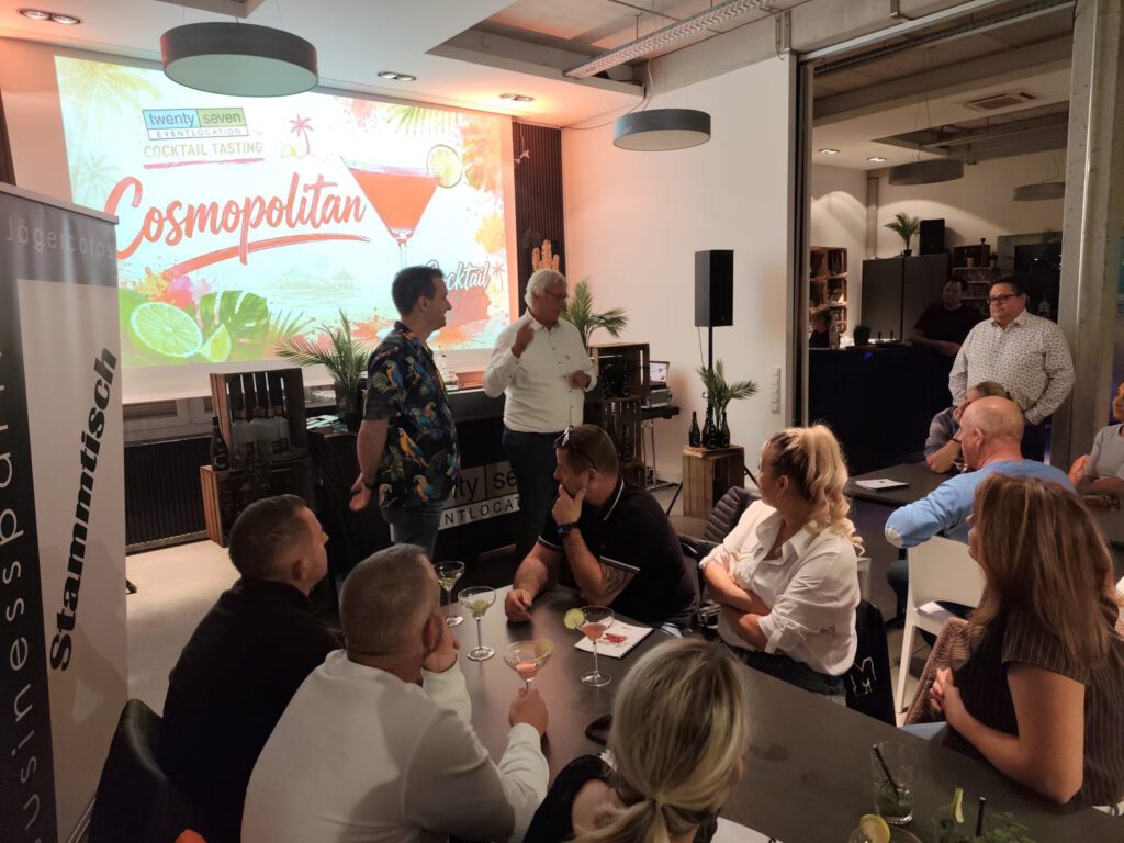 Vortrag vor den Gästen beim Cosmopolitan-Tasting, daneben ein Aufsteller des Jägercorps