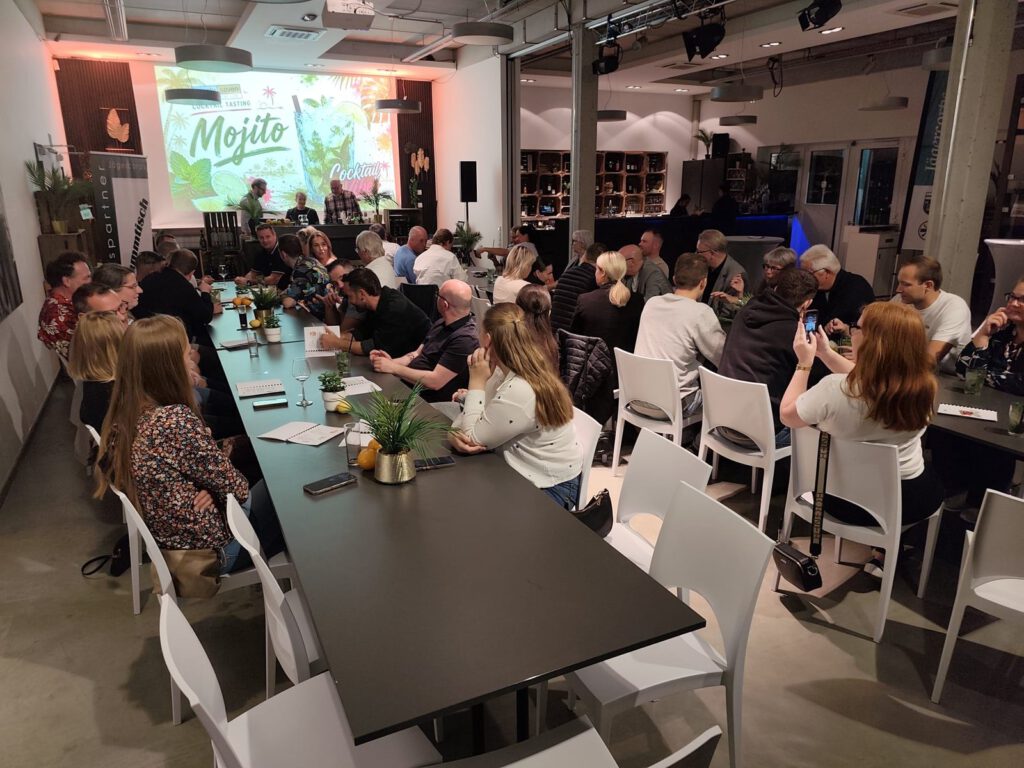 Voll besetzter Saal: Gäste an langen Tischen beim Mojito-Tasting